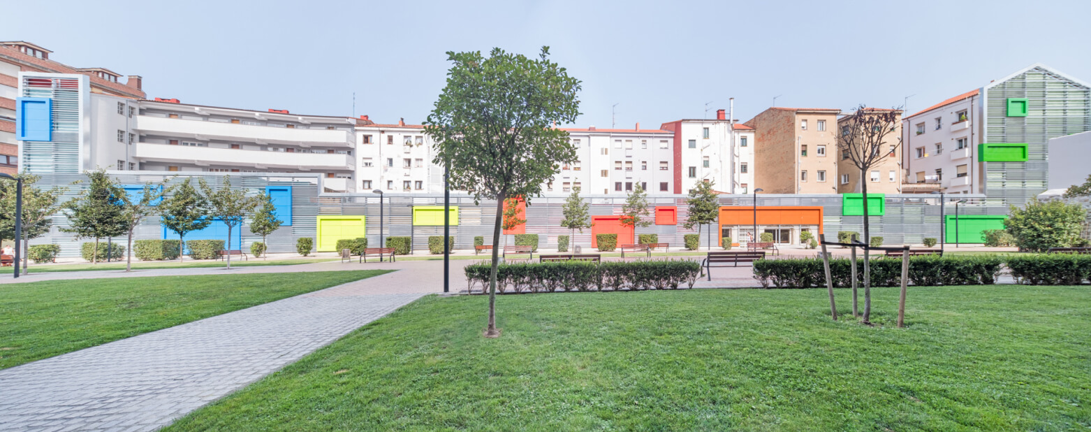 parque con arboles y bancos con edificios en el fondo